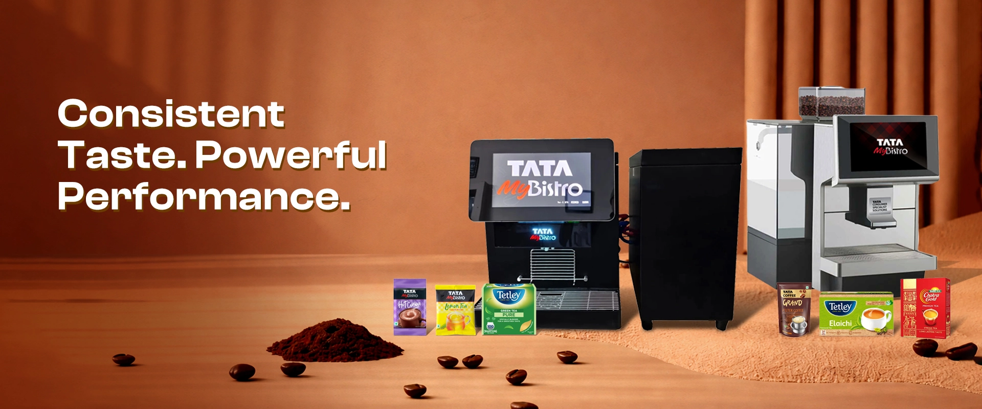 Coffee machines with "Tata myBistro" branding surrounded by product boxes and coffee beans on a wooden surface. Text reads "Consistent Taste. Powerful Performance."